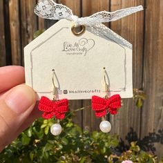 a pair of red bowknot earrings with pearls hanging from it's earwires