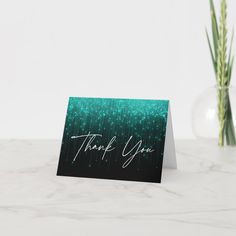 a thank you card sitting on top of a table next to a vase with flowers