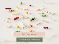 many different colored beads and charms on a white surface with the words fall connectors handmade in the us