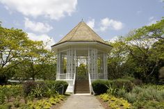 a white gazebo sitting in the middle of a lush green park