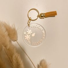 a close up of a keychain on a white surface with flowers and leaves