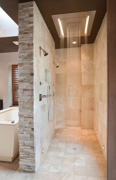 a walk in shower sitting next to a white tub