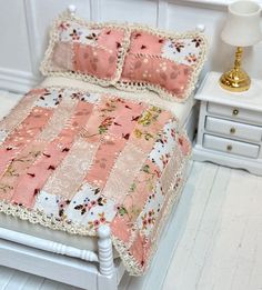 a dollhouse bed with pink and white quilted bedspread, nightstands and night stand