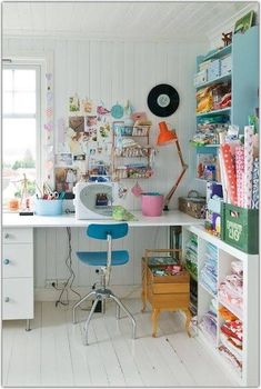 a white desk and chair in a room with lots of clutter on the shelves