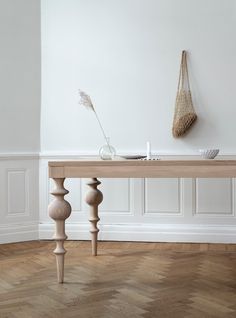 a wooden table sitting on top of a hard wood floor next to a white wall