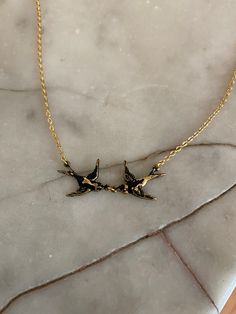 two birds on a branch necklace sitting on a marble slab