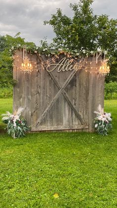 a wooden sign that says welcome with flowers and lights on it in front of some grass