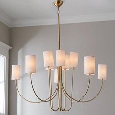 a chandelier hanging from the ceiling in a dining room with white linen shades