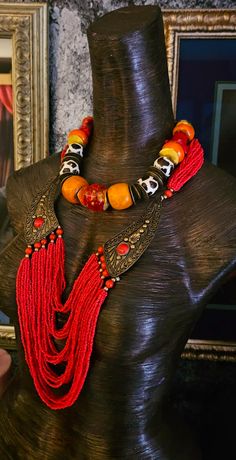 Here's a Bohemian Necklace and Bib Set I found in my inventory. The longer strand is a vintage piece that I did not make. It measures a non-adjustable 28" and closes with a button and a loop. Multiple strands of red-orange seed beads comprise the majority of the piece and two ornate metal accents (looks like bronze) are symmetrically set on each side with an orange-red cabochon (jade??). The shorter necklace is one that I made. It measures a non-adjustable 19" and features the following components: Tibetan resin, Moroccan resin, Zebu bone*, gold tone metal spacers, vintage Chinese brass coins, red branch corals, vintage brass beads and round tiger's eye. Closes with a gold tone hook and eye. Pair them together, or wear separately. These also will mix and match well with your personal favor Vintage Polished Beaded Necklaces For Festivals, Vintage Beaded Necklaces With Polished Beads For Festivals, Vintage Large Beads For Festivals, Unique Multi-strand Beaded Necklaces For Festivals, Unique Multi-strand Beaded Necklace For Festivals, Vintage Multi-strand Jewelry For Festivals, Vintage Polished Bead Jewelry For Festivals, Vintage Polished Beads Jewelry For Festival, Vintage Multi-strand Beaded Necklaces