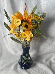 a blue vase filled with yellow flowers on top of a white cloth covered tablecloth