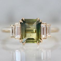 green sapphire ring $4,650 available at Gem Breakfast Green Sapphire Ring With Baguette Cut, Green Sapphire Baguette Cut Ring, Gia Certified Emerald Cut Green Sapphire Ring, Gia Certified Emerald-cut Green Sapphire Ring, Emerald Cut Green Sapphire Ring, Opalescent Sapphire, Gem Breakfast, Unique Gemstone Engagement Rings, Green Sapphire Ring