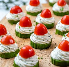 cucumbers with tomatoes and cream cheese on them are arranged on a wooden board