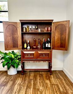 a wooden cabinet sitting next to a potted plant on top of a hard wood floor