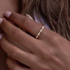 a woman's hand wearing a gold ring with pearls on the middle and side