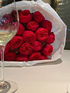 a bouquet of red roses and a glass of wine