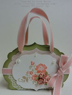 a handbag with pink flowers and ribbons on the front, sitting on top of a white table