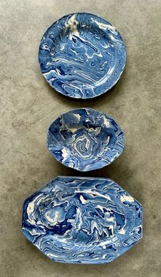 three blue plates sitting on top of a cement floor