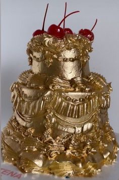 there is a gold cake with cherries on the top and two cherries on the bottom