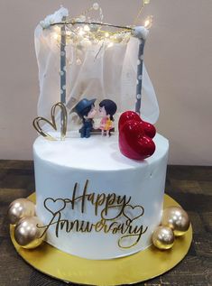 a wedding cake decorated with two hearts and the words happy anniversary written on it in gold lettering