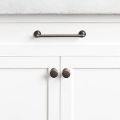 a close up view of the handles on a white cabinet with dark metal knobs