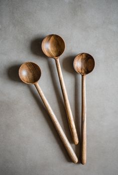 three wooden spoons sitting next to each other on top of a gray countertop