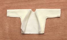 a piece of cloth is folded on top of a wooden surface with white stitching