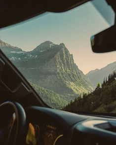 the view from inside a car looking at mountains and trees