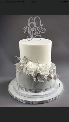 a white wedding cake with flowers and the number 60 on it's top tier