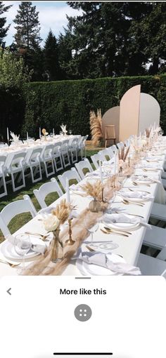 the table is set up with white chairs and place settings for an outdoor dinner party