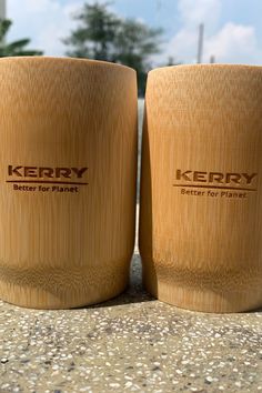 two wooden cups sitting next to each other on top of a cement ground with trees in the background