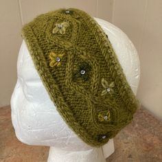 a knitted headband with buttons on top of a mannequin's head