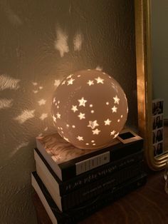 a lamp sitting on top of a stack of books in front of a mirror with stars