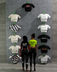 two people standing in front of a wall with t - shirts on it