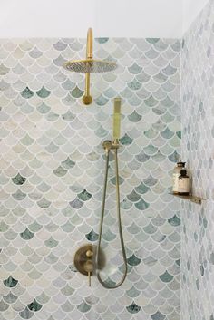 a shower head and hand held shower faucet in a bathroom with fish scale wallpaper