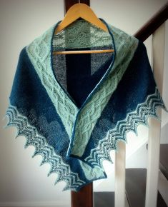 a blue and green shawl hanging on a wooden rail