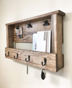 a wooden shelf with hooks on it and some keys hanging from the wall behind it