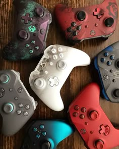 several different colored video game controllers on a table