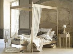 a bedroom with four poster bed and white curtains