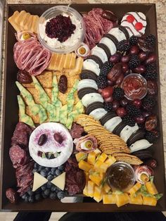 an assortment of cheeses, meats, and fruit arranged in a large platter