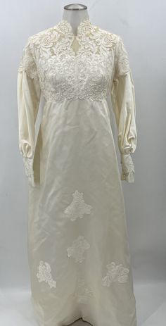 a white dress on a mannequin with laces and flowers in the front