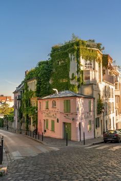 a pink building with ivy growing on it's side and cars parked in front