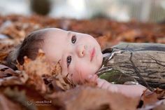 a baby laying on top of leaves in the grass