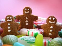 three gingerbread men are standing in front of candy