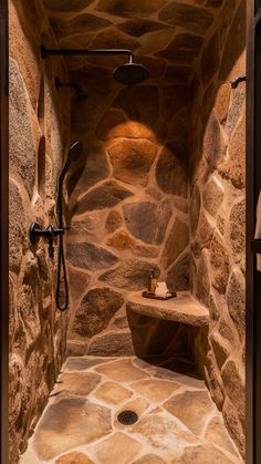 a bathroom with stone walls and flooring is shown in this image, it has a shower