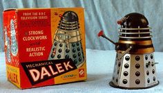 a metal dalek toy next to a box