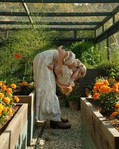 a woman bending over in a garden filled with flowers