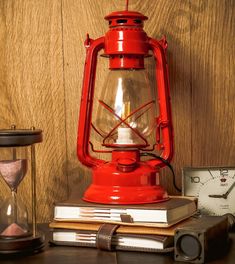 a red lantern sitting on top of a table next to an alarm clock and books