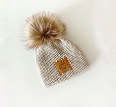 a white hat with a brown fur pom