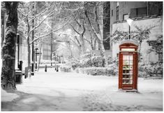 a red phone booth sitting in the middle of a snow covered street