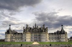 an old castle with many towers and turrets on it's sides, against a cloudy sky